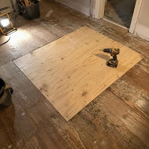 New plywood patch screwed into old subfloor during floor and subfloor repair