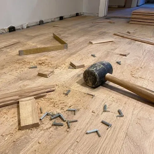 Offcuts, cleats and mallet on new hardwood during hardwood floor installation