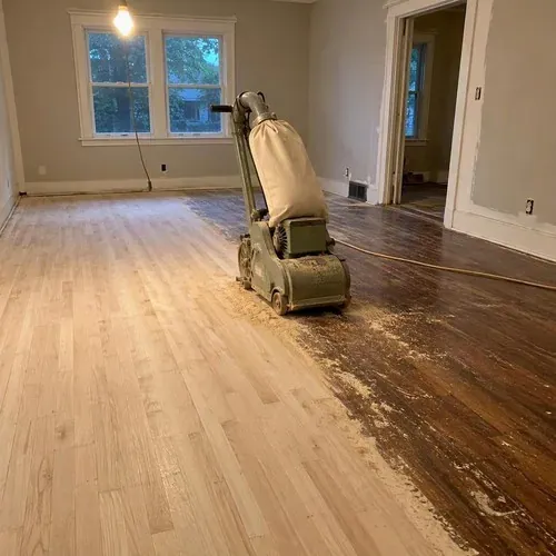 Drum sander on half-sanded hardwood floor during hardwood floor sanding and refinishing