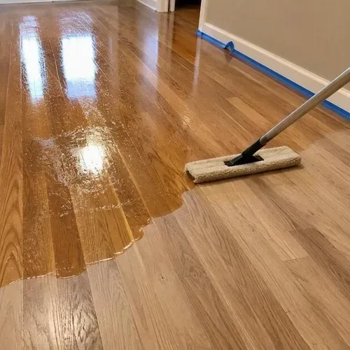 Wet polyurethane coat applied with pad during hardwood floor sanding and refinishing