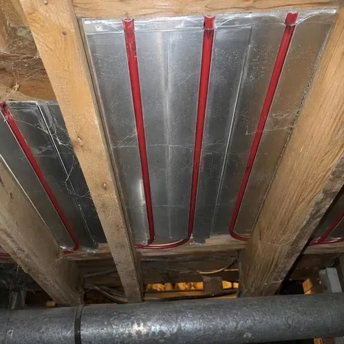 Heat transfer plates with PEX under subfloor during radiant heated floor installation