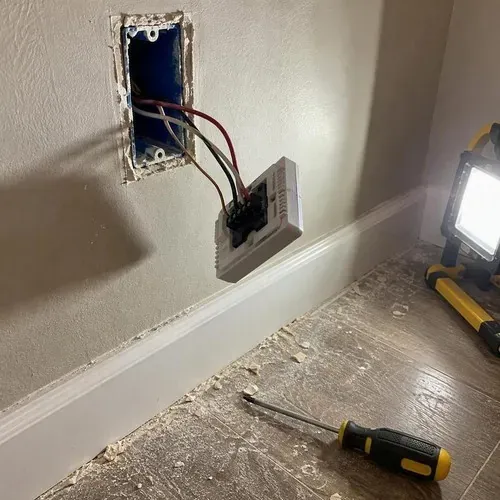 Floor heating thermostat wiring hanging from wall box during radiant heated floor installation