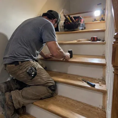 Carpenter fitting new oak tread on staircase during stair and railing installation
