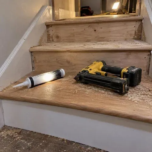 Construction adhesive and nail gun on stairs during stair and railing installation