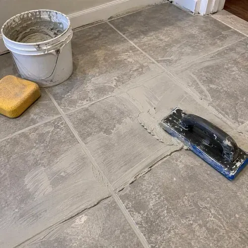 Grout spread with rubber float over new tile during ceramic and porcelain tile installation