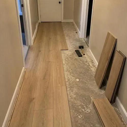 Laminate planks half-installed in a hallway during vinyl and laminate flooring installation